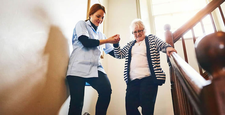 "The average annual salary is somewhere around £30,000, and entry level pay is normally around £25,000" A nurse helps an elderly person walk down stairs in a care home